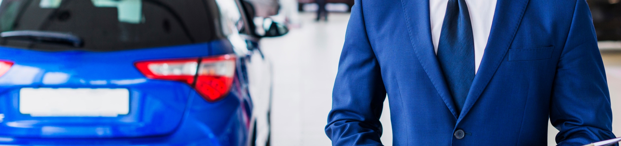 a man smiles in front of a blue sedan